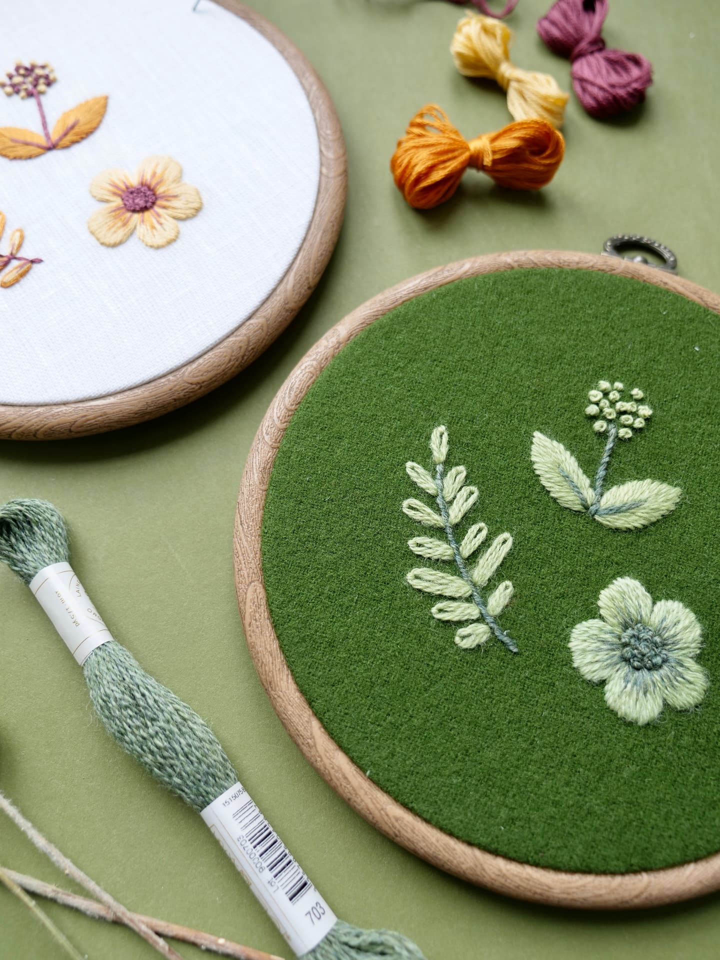 Broderirammer med blomstermotiv og fargerike garnnøster